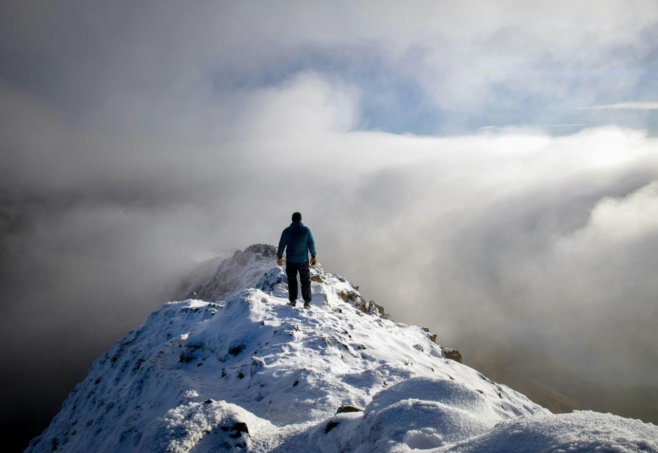 En solovandrer over skyene på toppen av Snowdonia, Wales, Storbritannia